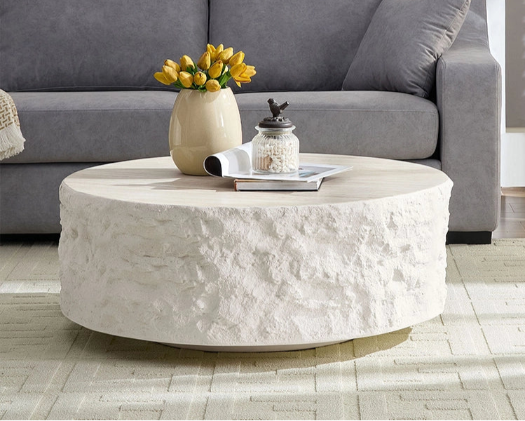 Living room with a gray sofa, round stone coffee table, and decorative items.