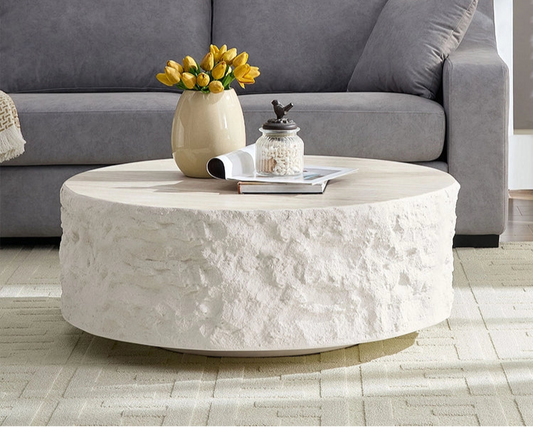 Living room with a gray sofa, round stone coffee table, and decorative items.